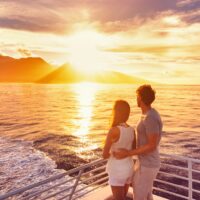 Travel cruise ship couple on sunset cruise in Hawaii holiday. Two tourists lovers on honeymoon travel enjoying summer vacation. Travel cruise ship couple on sunset cruise in Hawaii holiday. Two tourists lovers on honeymoon travel enjoying summer vacation.